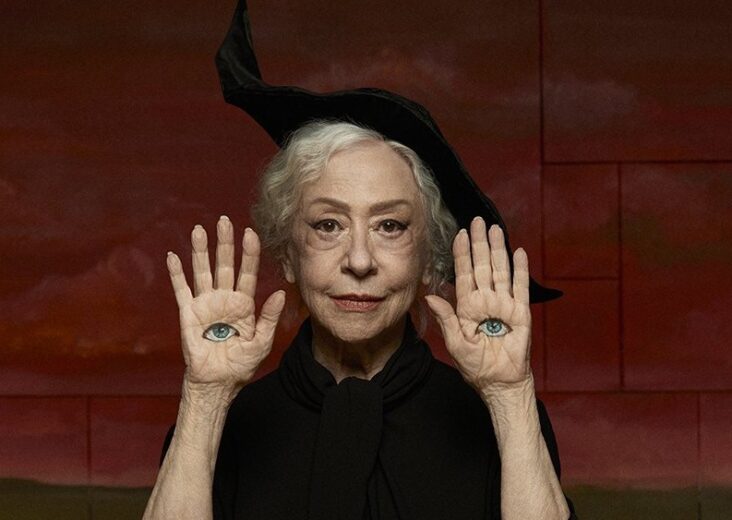 Fernanda Montenegro Maquiada e com as mãos erguidas, com desenhos de olhos em suas mãos