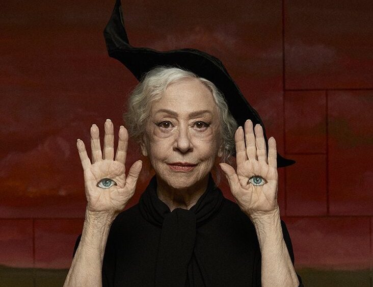 Fernanda Montenegro Maquiada e com as mãos erguidas, com desenhos de olhos em suas mãos